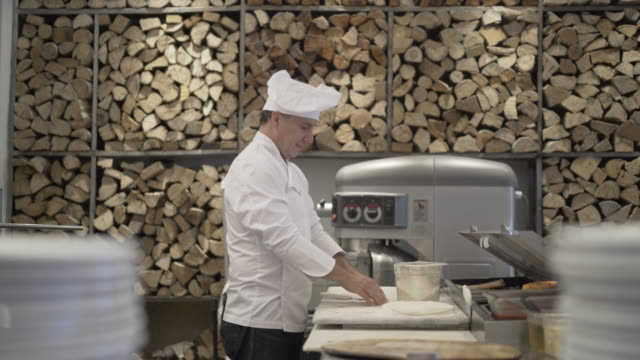 Male chef preparing a pizza and kneading the dough