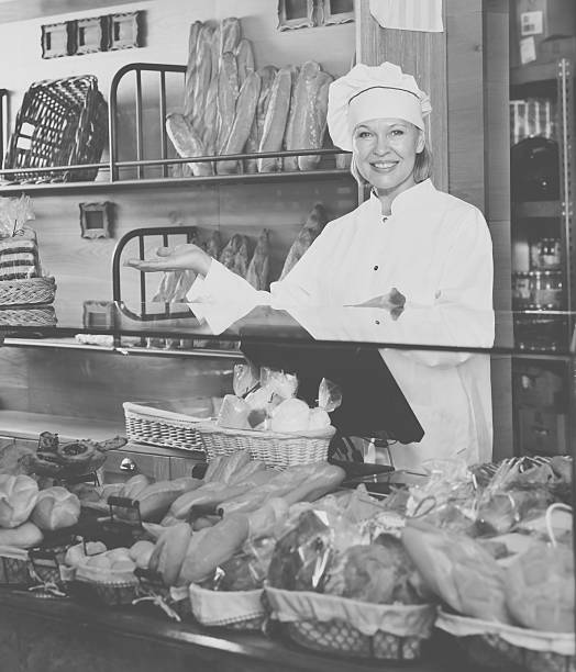 Senior woman at bakery display Portrait of friendly senior woman at bakery display with a pastry old candy store stock pictures, royalty-free photos & images