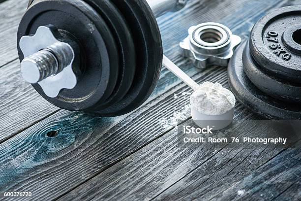 Classic Dumbbell With Protein Powder On Rustic Wooden Table Stock Photo - Download Image Now