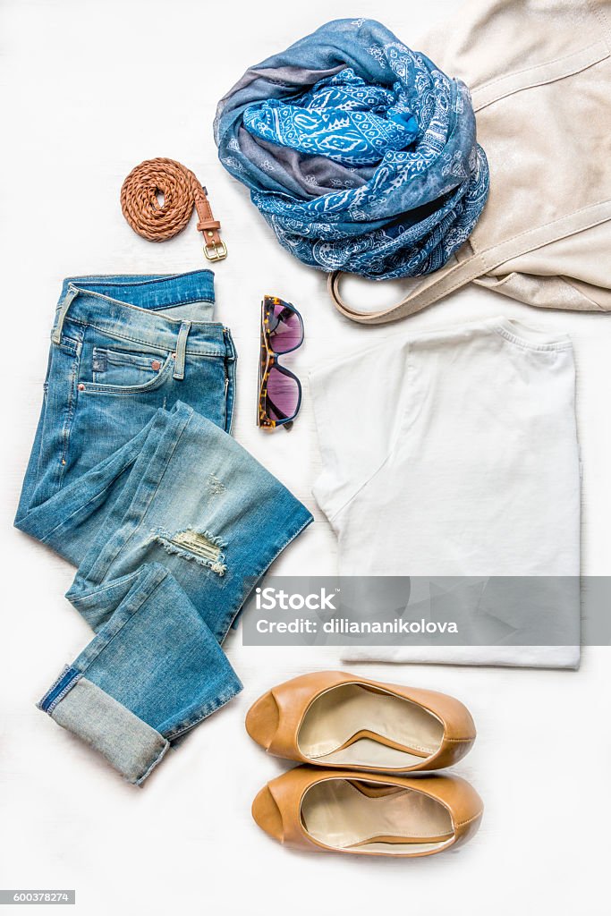 Collage of female clothing set. Jeans, top, shoes and accessories. Collage of female clothing set.  Ripped jeans, white top, brown high heels shoes and accessories over white wood background. Clothing Stock Photo