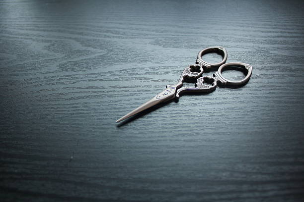 istock Decorated black scissors on black wood background 600381192