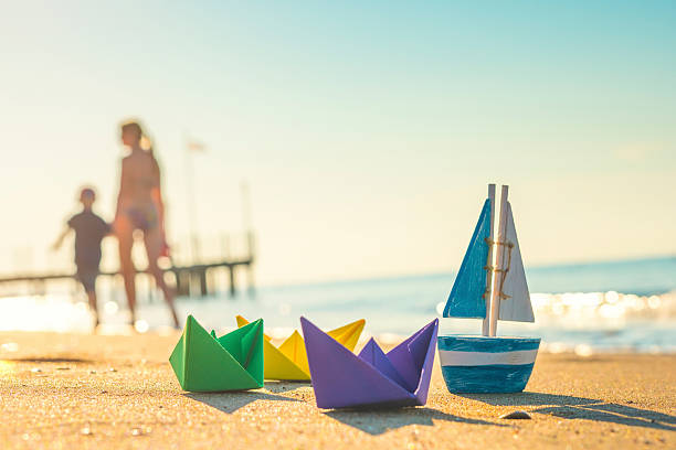 barcos de papel, botes de madera y gente caminando en la playa - foto de stock