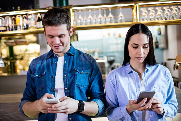 istock Man and woman using cellphone in bar 600384338