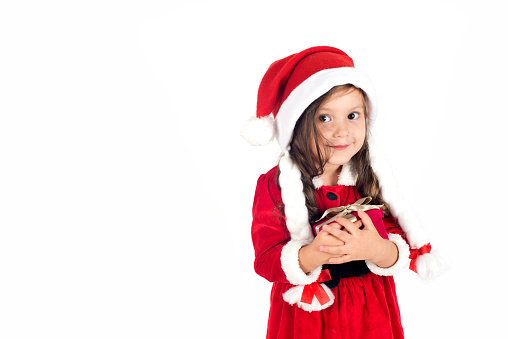 Little girl in santa claus costume is holding a gift box.