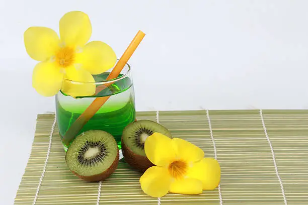 Photo of Two tone of kiwi juice served with halves kiwi on bamboo.