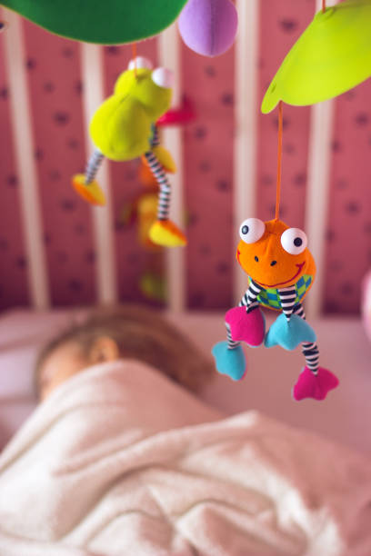 istock Baby bed with mobile toy above it; baby sleeping 600388670