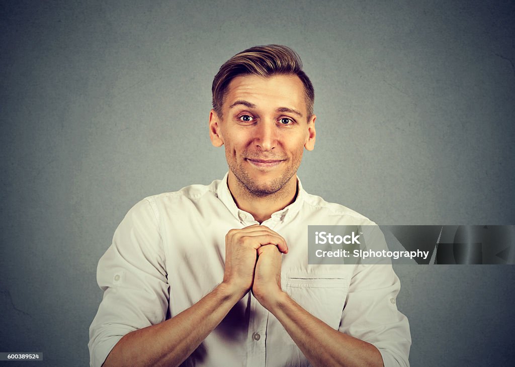 man showing clasped hands, pretty please Kind young man showing clasped hands, pretty please isolated on gray background. Human emotion facial expression feelings, body language Adult Stock Photo