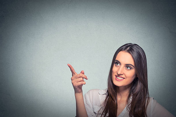 istock woman looking up pointing finger at blank copy space 600390200