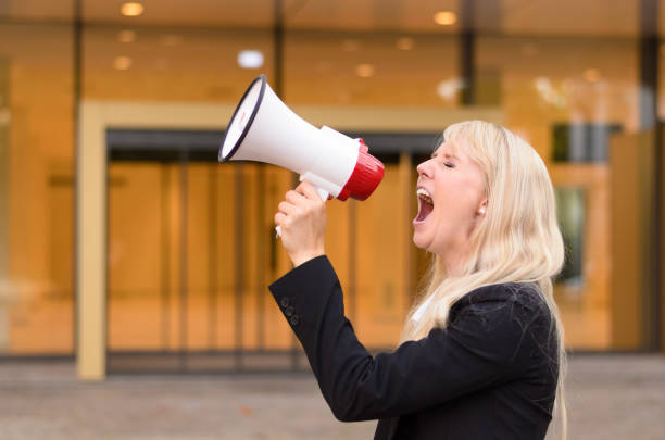 istock Angry woman protester yelling into a megaphone 600394320