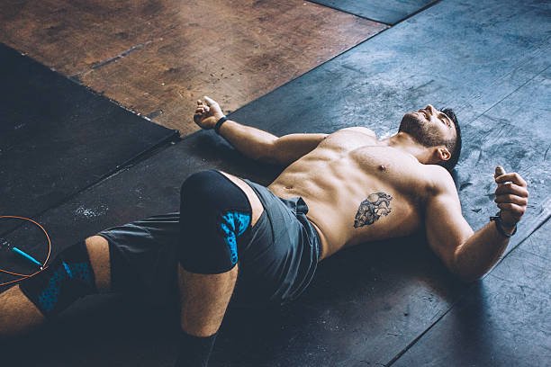 No pain, no gain! Young athlete resting in gym after hard cross training. Wearing professional sport clothing . man reclining stock pictures, royalty-free photos & images