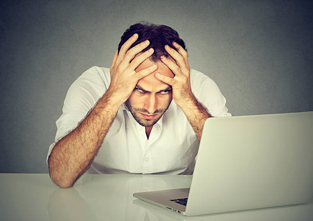 istock Stressed man sitting at his desk in front of computer 600399512