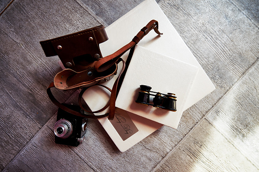 Photobook in bright leather, retro binoculars and old camera. Creative atmosphere