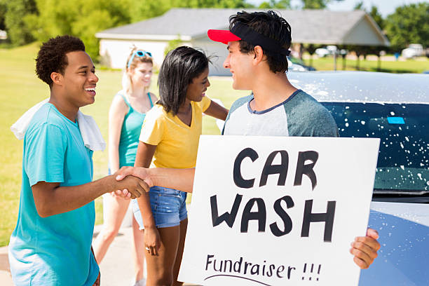 istock Friends greet one another during charity car wash event 600403280