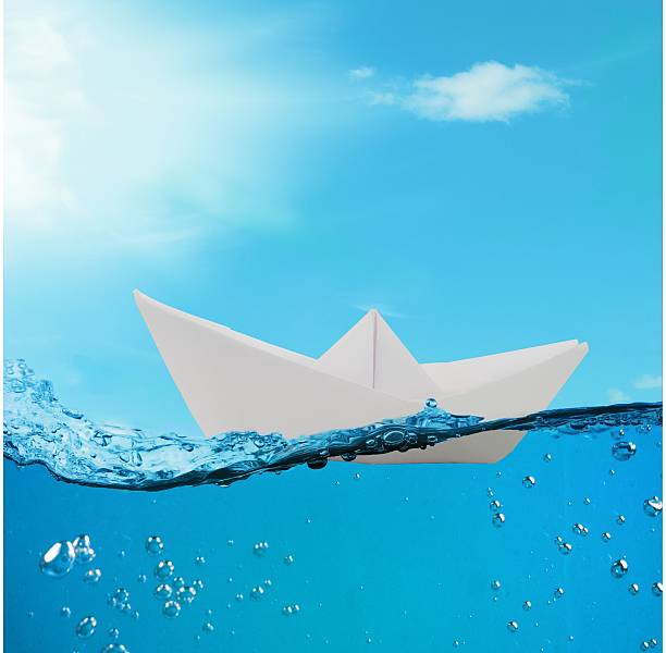 istock paper boat floating among the waves in the ocean 600403864