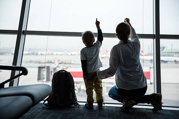 Mother and son looking through window in airport stock photo