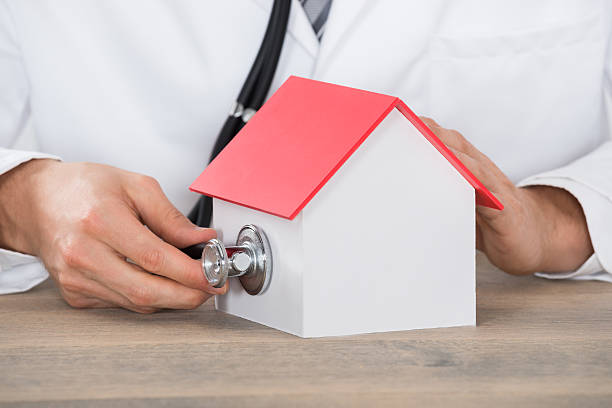 istock Doctor Hand Holding Stethoscope On House Model 600406218