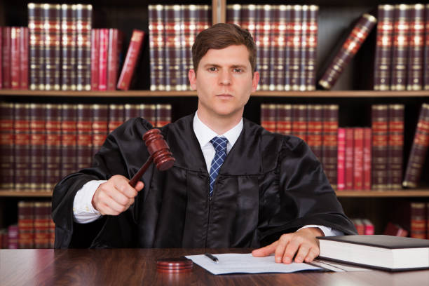 istock Confident Young Judge Striking The Gavel At Table 600408200