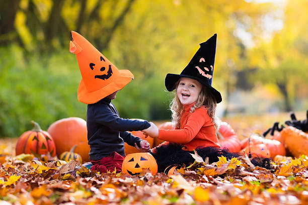 istock Kids wearing witch costumes with pumpkins on Halloween 600409040