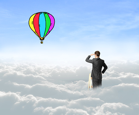 businessman on cloud looking on air baloon
