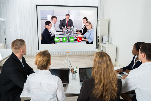 Group Of Businesspeople Together Videoconferencing At Workplace