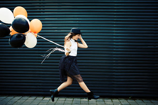 Girl dressed for Halloween jumping with balloon