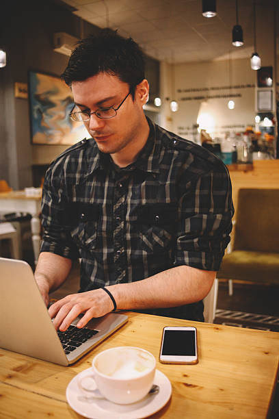istock Young man sitting in a coffee shop using laptop 600414222