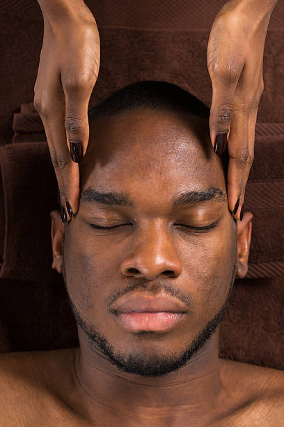 Man Getting Forehead Massage In Spa Close-up Of Young African Man Getting Forehead Massage In Spa black male massage stock pictures, royalty-free photos & images