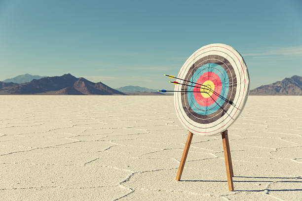 Bow and Arrow Target with Arrows A target with several arrows in the bullseye stands on the Bonneville Salt Flats. The business has found success and it mark for the future.  arrows pointing up stock pictures, royalty-free photos & images