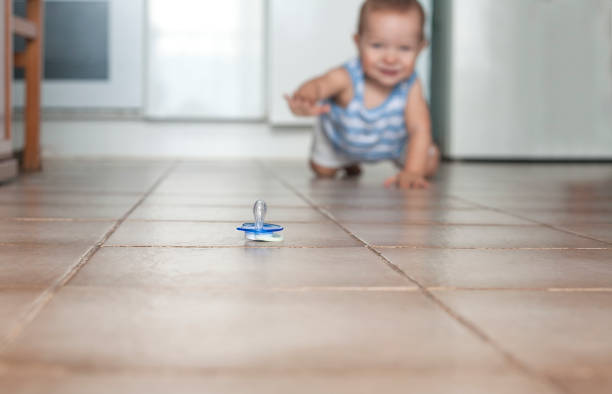 Happy baby boy crawling to grab the pacifier. Hygiene at home concept