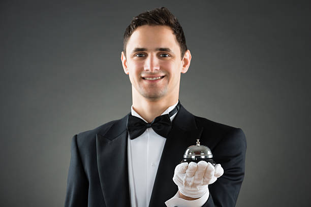 istock Smiling Waiter Holding Service Bell 600416692