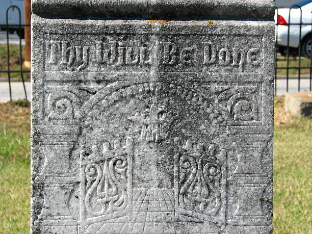 istock Weathered carving with gates and text on an old headstone 600416938