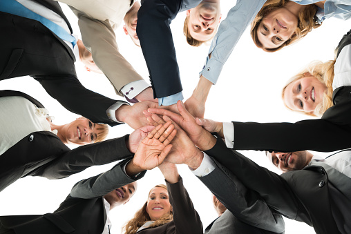 Directly below portrait of confident business team stacking hands against white background