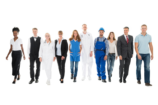 Full length portrait of confident people with various occupations walking in row against white background