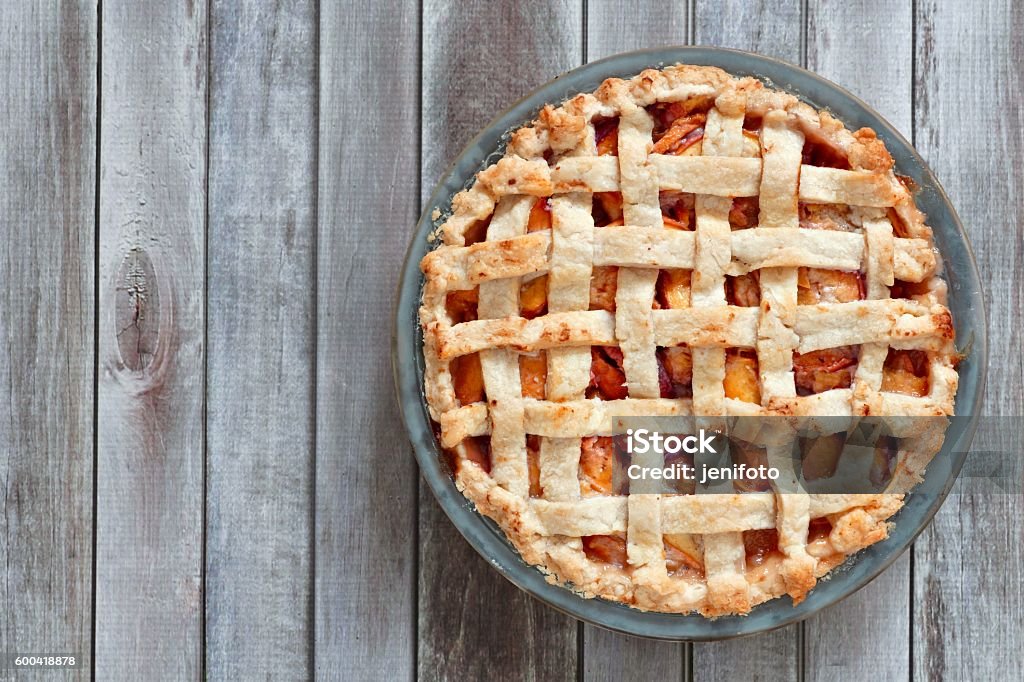 Rustic homemade peach pie, above view on wood Rustic homemade peach pie in baking plate, above view on a wood background Sweet Pie Stock Photo