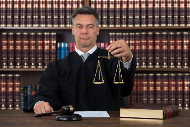 istock Judge Holding Justice Scale At Table In Courtroom 600669344