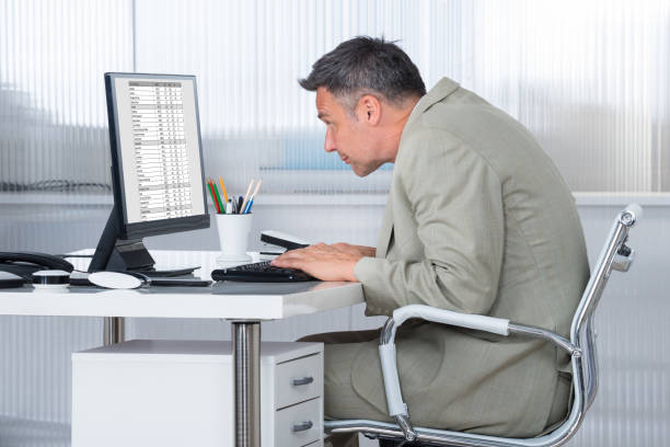 Concentrated Businessman Using Computer At Desk Side view of concentrated businessman using computer at desk in office posture photos stock pictures, royalty-free photos & images