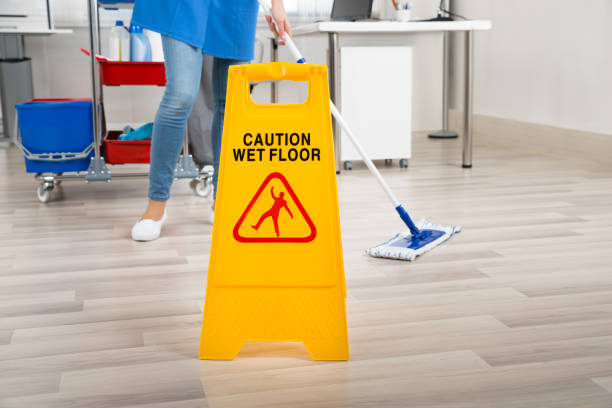 istock Janitor Mopping Floor By Wet Caution Sign In Office 600671722