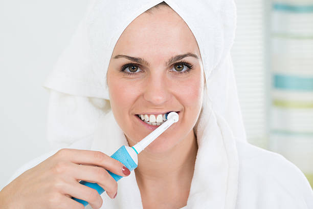 istock Woman Brushing Teeth With Electric Toothbrush 600672546