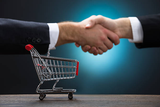 istock Shopping Cart On Table With Businessmen Shaking Hands 600675408