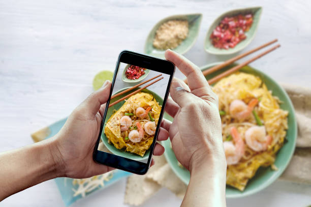 Taking photo of pad thai with smart phone. Taking photo of pad thai (Stir fry noodles with shrimp) with smart phone. peoples alliance for democracy stock pictures, royalty-free photos & images