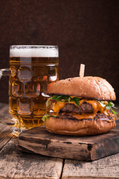 istock Fresh hamburger with a beer on a wooden table. 600684218