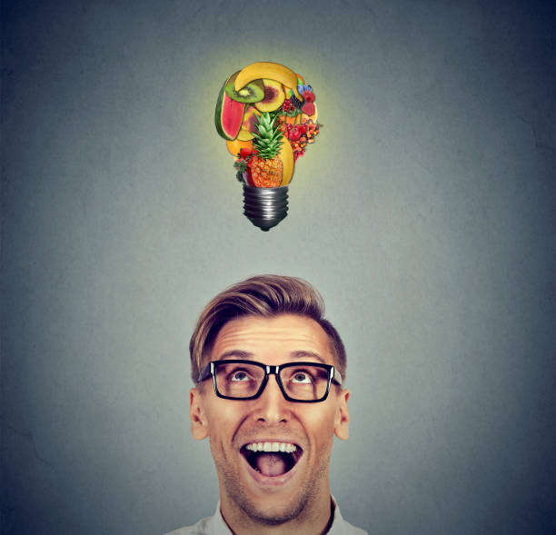 istock Eating healthy. Man looking up at fruit light bulb 600687412