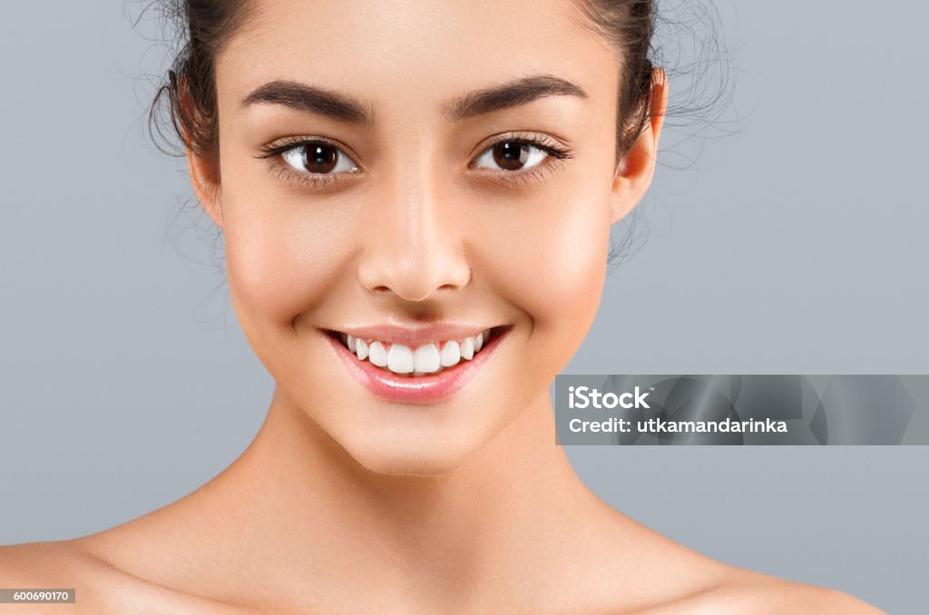Beautiful Face of young woman with perfect skin. Gray background Beautiful Face of Young Woman Model with Clean Fresh Perfect Healthy Skin. Age and Health Concept. Beauty Woman Portrait isolated on gray background Human Face Stock Photo