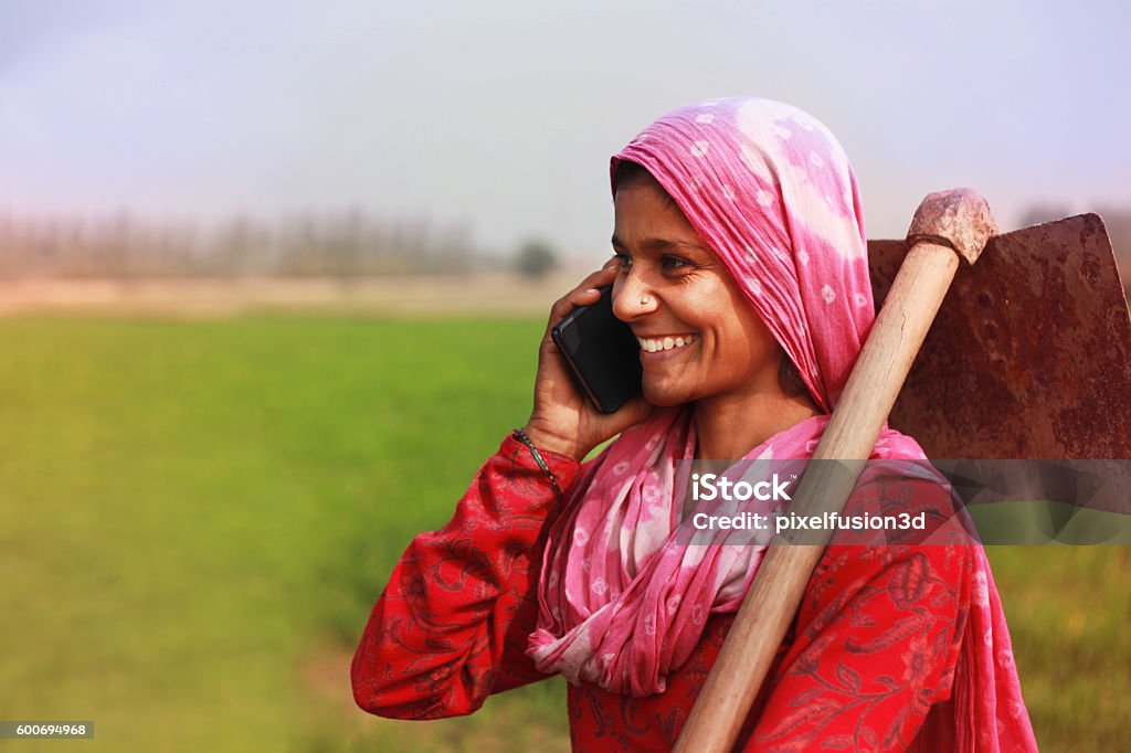 Women farmer talking on smart phone Cheerful traditional Village women standing in green wheat field and talking on the mobile phone. She looking so happy when she talking on the phone.  India Stock Photo