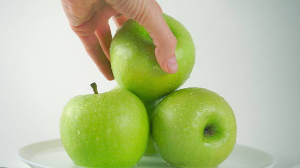 istock Girl's hand taking one wet green apple, light background 600694980