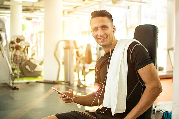 istock Handsome young man with headphones using smartphone in a gym. 600696514