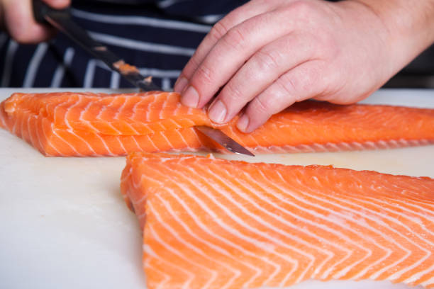istock Chef cutting salmon fish on fillets with knife 600698330