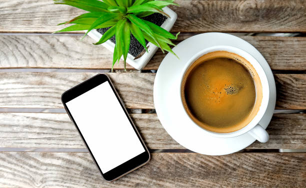 istock Smart phone and white coffee cup with flowerpot on wooden. 600699716