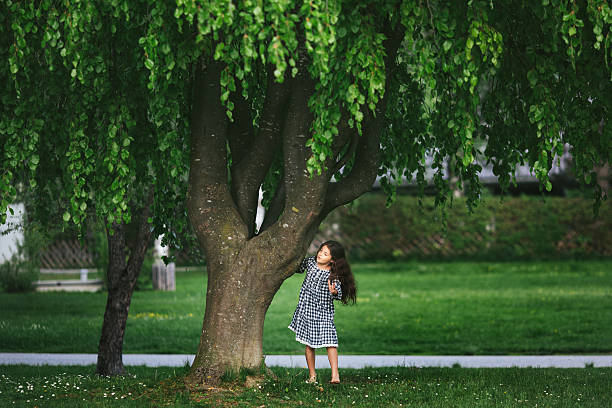 Little cute girl running around near the big tree