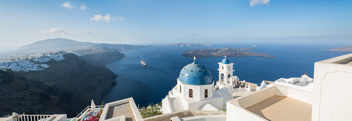 Early morning view in Santorini of the Imerovigli church sitting on top of the volcanic caldera. Santorini in Greece is one of the most famous travel destination in the World with numerous cruise ships anchoring in the bay below. The architecture is also famous for the duotone colors of the white painted buildings and light blue details.